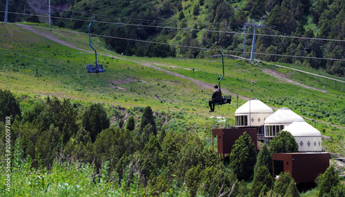 Fotografie person traveling on a chairlift in the mountains, yurts on the background