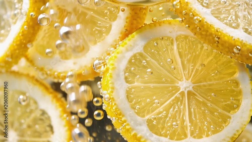 Fresh lemon slices in sparkling water with bubbles creating vibrant citrus beverage background texture