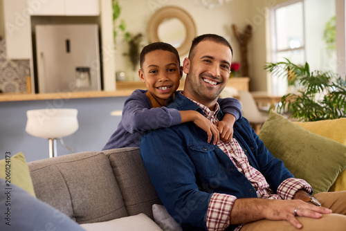 Happy and smiling black boy embracing from behind his father