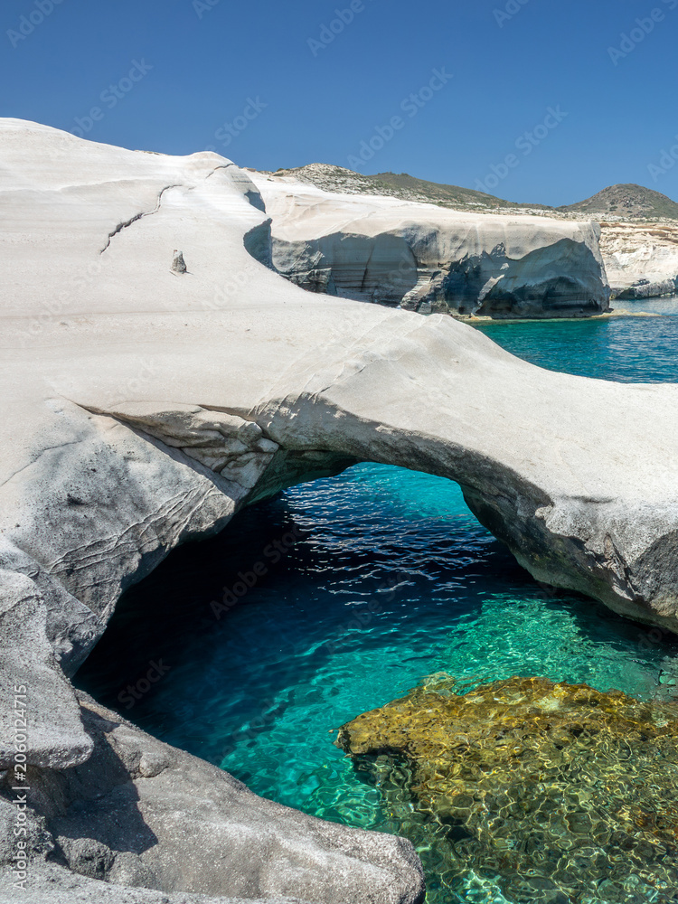 Fototapeta premium Sarakiniko beach, or moon beach with a natural arch of white volcanic rocks and transparent water in Milos, Cyclades Islands, Greece