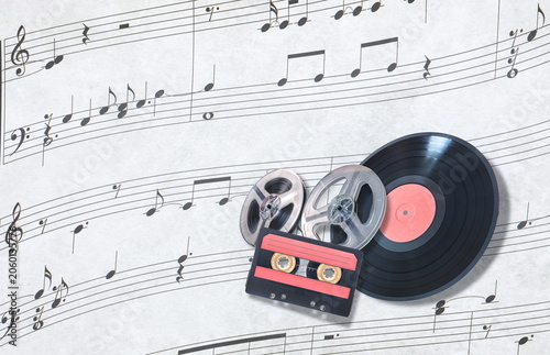 audio cassette bobbins and vynil on musical score background