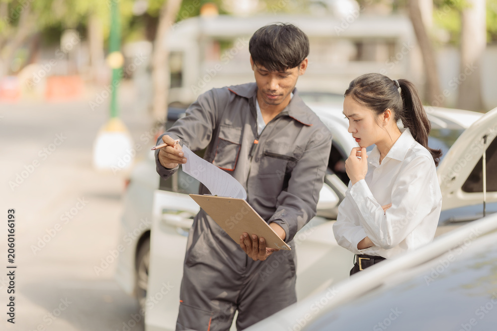 Fototapeta premium The insurance agent showed the anxious female driver at the scene of the car accident details on his smartphone, emphasizing the claims process to the Asian businesswoman after the collision.