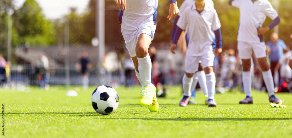 Naklejka premium Youth Soccer Action Shot: Close-Up of Kids Running and Dribbling Ball on Green Pitch