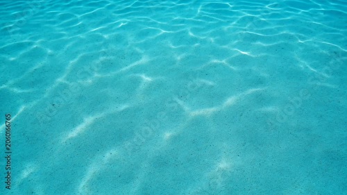 Clear blue pool water with gentle sunlight reflections. Summer texture, luxury resort atmosphere and refreshing background concept.