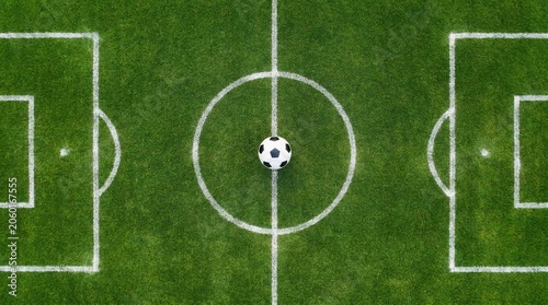 Top down view of a soccer ball on the center circle of a green field
