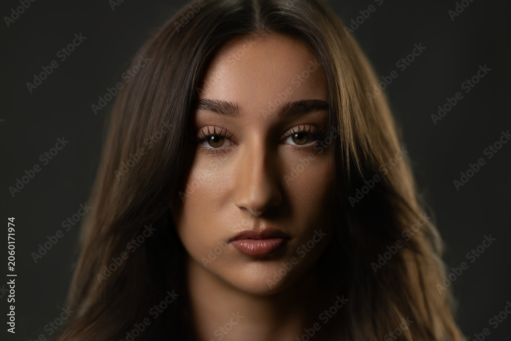 Fototapeta premium Young woman posing in a studio closeup, looking directly at camera with intense expression