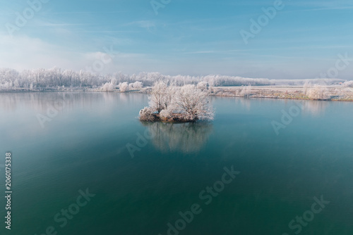 Cuadro en lienzo Île givrée sur lac calme en hiver, vue aérienne drone