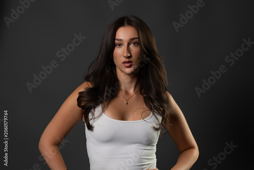 Confident brunette model wearing a white tank top posing for beauty and fashion concepts