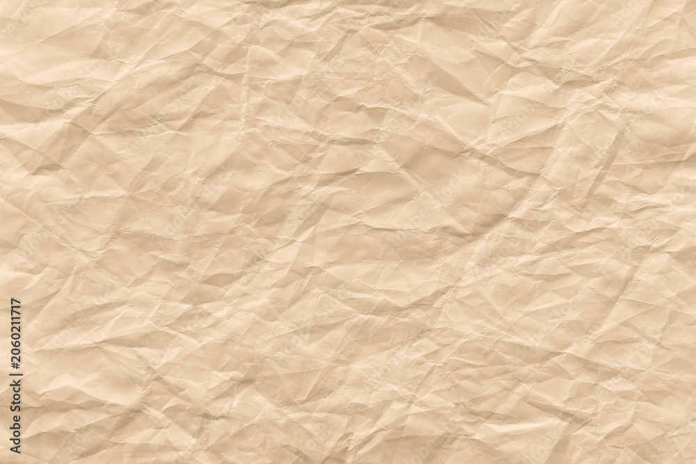 Fototapeta premium Crinkled beige paper texture background with soft, wrinkled folds.