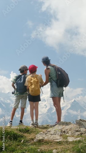 Mother teaching her two sons about the mountains during a family hiking trip, pointing towards the majestic snowy peaks of mont blanc in the beautiful european alps