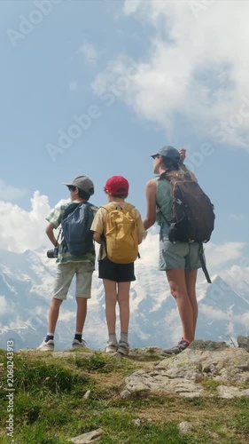 Mother and two sons hiking in the mountains enjoying the view of the snow-capped peaks, a perfect family bonding activity for an adventurous summer vacation