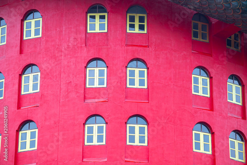 Symmetrical Windows on Pink Dragon Tower at Wat Samphran,multiple yellow-framed windows on the curved pink facade of the iconic dragon temple building in Nakhon Pathom provice,Thailand.