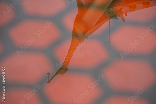 Artistic abstract reflection of a traditional Thai temple pagoda or roof finial on a wet tiled floor with red tones.