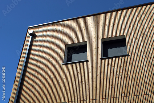 Bâtiment à l’esthétique contemporaine avec bardage bois vertical et store de fenêtre enrouleur occultant en toile tissu noir