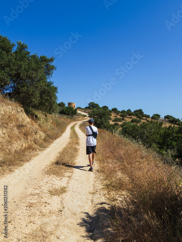 Brave 11 year old boy wearing an arm brace walking on a path towards the Gournes Gouvon viewpoint during a summer vacation in Crete, Greece