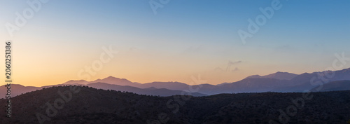 Beautiful sunrise over mountains in Crete, Greece, showcasing majestic layers of silhouetted hills under a colorful morning sky