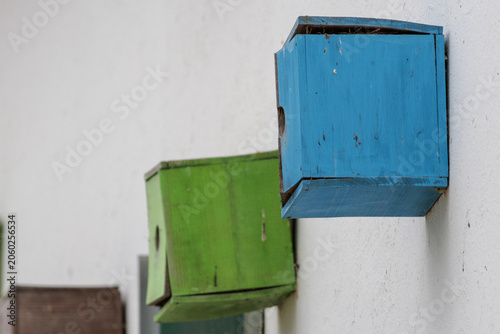 Blue and green wooden birdhouses mounted on white wall