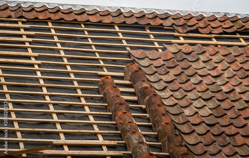Clay roof tile repair and replacement on old house during roof renovation
