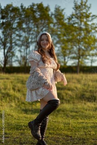 Tablou pe pânză Young woman in a stylish dress poses gracefully in a sunlit field surrounded by