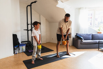 Father teaching young son how to lift kettlebells
