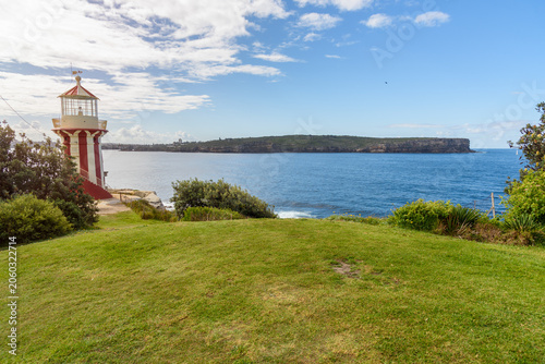 Historic clifftop striped lighthouse at the entrance of Sydney harbour on a sunny autumn day. NSW, Australia.