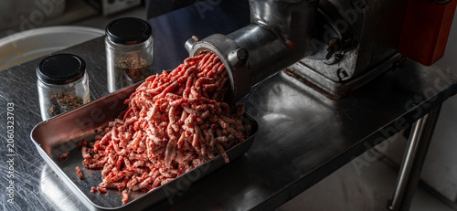 Close up video of fresh ground beef being processed through a commercial meat grinder in a professional kitchen