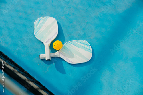 Two Pickleball Paddles and Ball Resting on Outdoor Court Before Match
