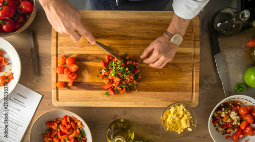 Top view of fresh vegetables being chopped on a wooden cutting board, showcasing healthy cooking, meal preparation, and nutritious ingredients.

