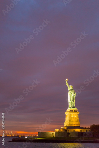 Statue of Liberty illuminated at twilight serves as a landmark destination for global travel and tourism on Liberty Island, New York City, USA.