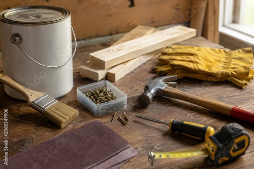 DIY woodworking tools and materials on rustic workbench with paint can brush hammer screwdriver and lumber