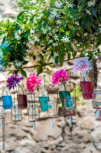 Colorful flower arrangement in hanging glass bottles outdoors
