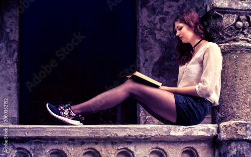 Young woman reading a book in historic architecture setting