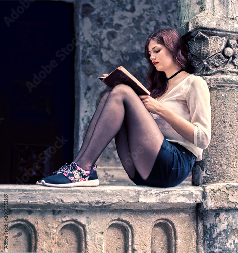 Young woman reading a book in historic architecture setting