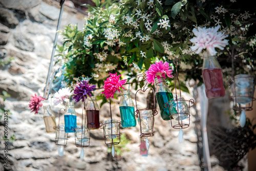 Rustic wedding decoration with floral arrangement in hanging glass bottles