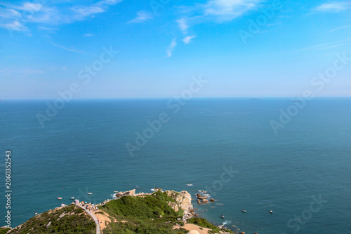 Foto Tranquil wide seascape with rocky green headland and calm blue ocean