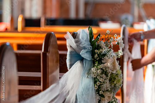 Billede på lærred Close up of hands arranging flowers, foliage and tulle on a church pew for weddi