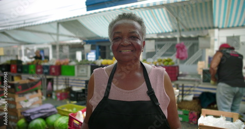 African American elderly woman portrait at outdoor produce market smiling gently and reflecting pride familiarity and human presence in everyday local street commerce