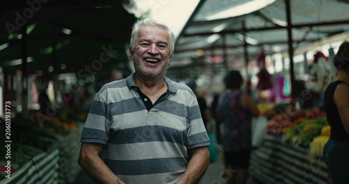 Φωτογραφία Elderly man smiling warmly at outdoor street market surrounded by produce stalls