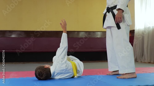 A little athlete practices exercises near a trainer