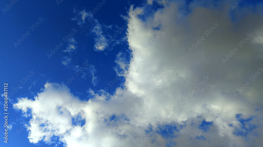 Obraz premium Large white clouds floating across a deep blue sky, creating a serene and refreshing natural background ideal for weather, nature, and environmental themes.