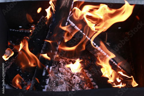 Burning logs with hot flames inside outdoor grill