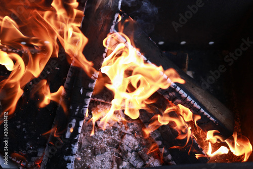 Burning firewood with orange flames and hot charcoal embers