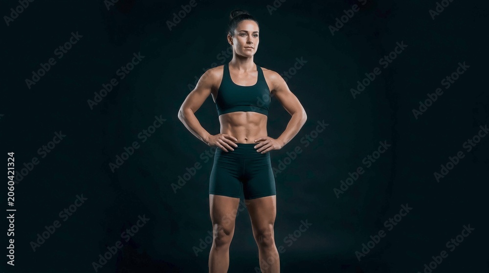 Fototapeta premium Fit Female Athlete Standing Confidently with Hands on Hips in Studio