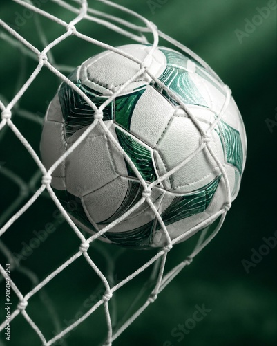 Soccer ball hitting goal net after goal score. Green and white ball in stadium mesh. Professional championship 2026 match action. Sports competition and victory celebration concept