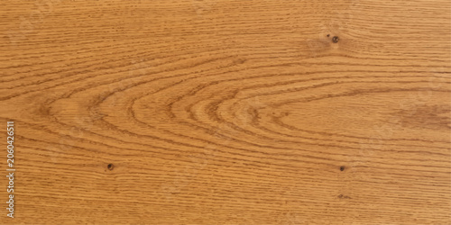 A close-up view showcases the natural grain and texture of a warm, honey-toned wooden surface, highlighting its organic beauty and detailed pattern.