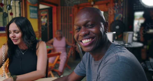 Φωτογραφία African American man smiling at café table while chatting with friends conveying