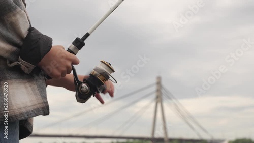 A little boy is fishing on a big river using a spinning rod	