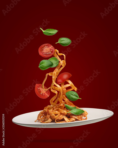 Bild auf Leinwand Flying pasta with tomato basil levitation food, red background