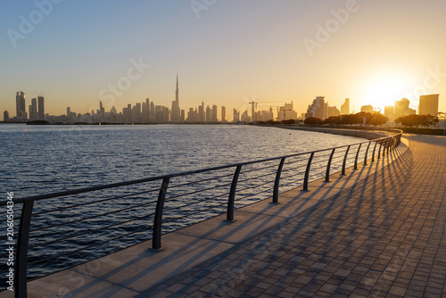 Sunset view from Al Jaddaf Walk waterfront promenade overlooking Dubai skyline and Burj Khalifa, with golden evening light reflecting across Dubai Creek