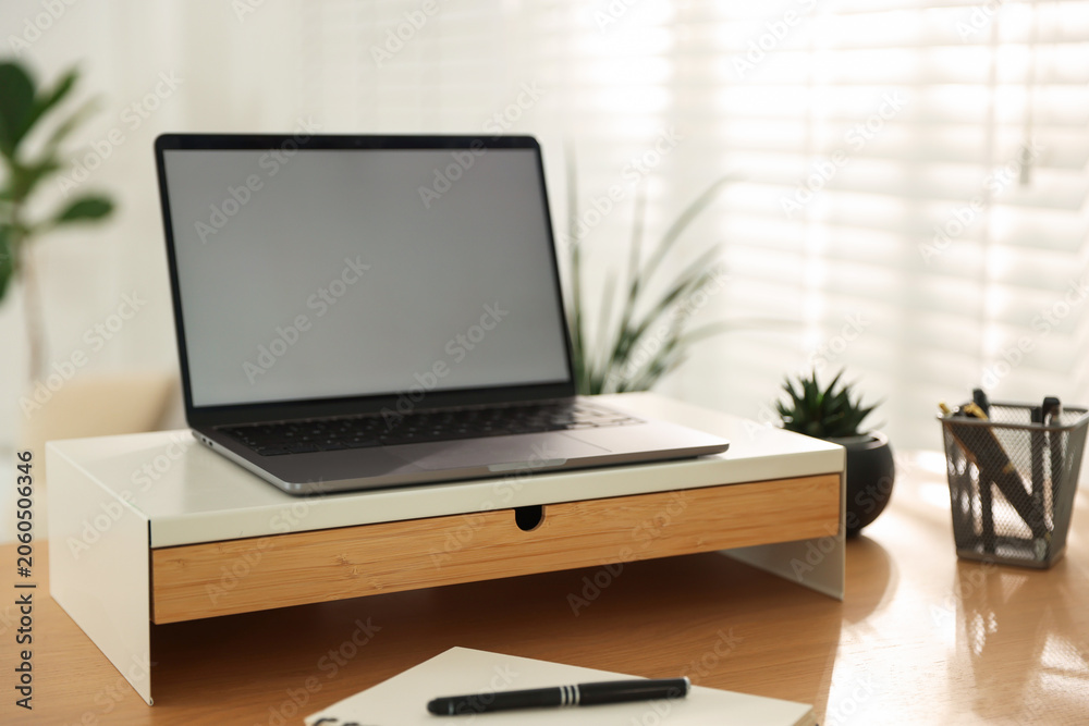 Fototapeta premium Workplace with laptop on riser stand and stationery indoors, closeup